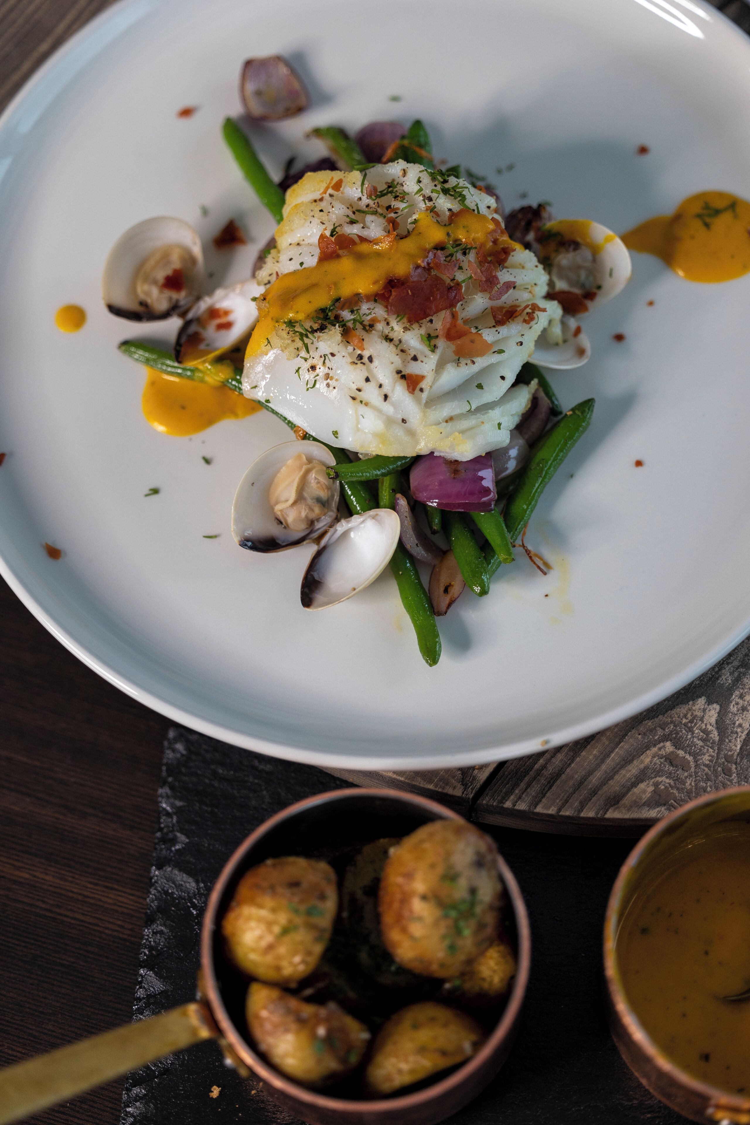 A plate of food with clams, green beans, and a poached egg.