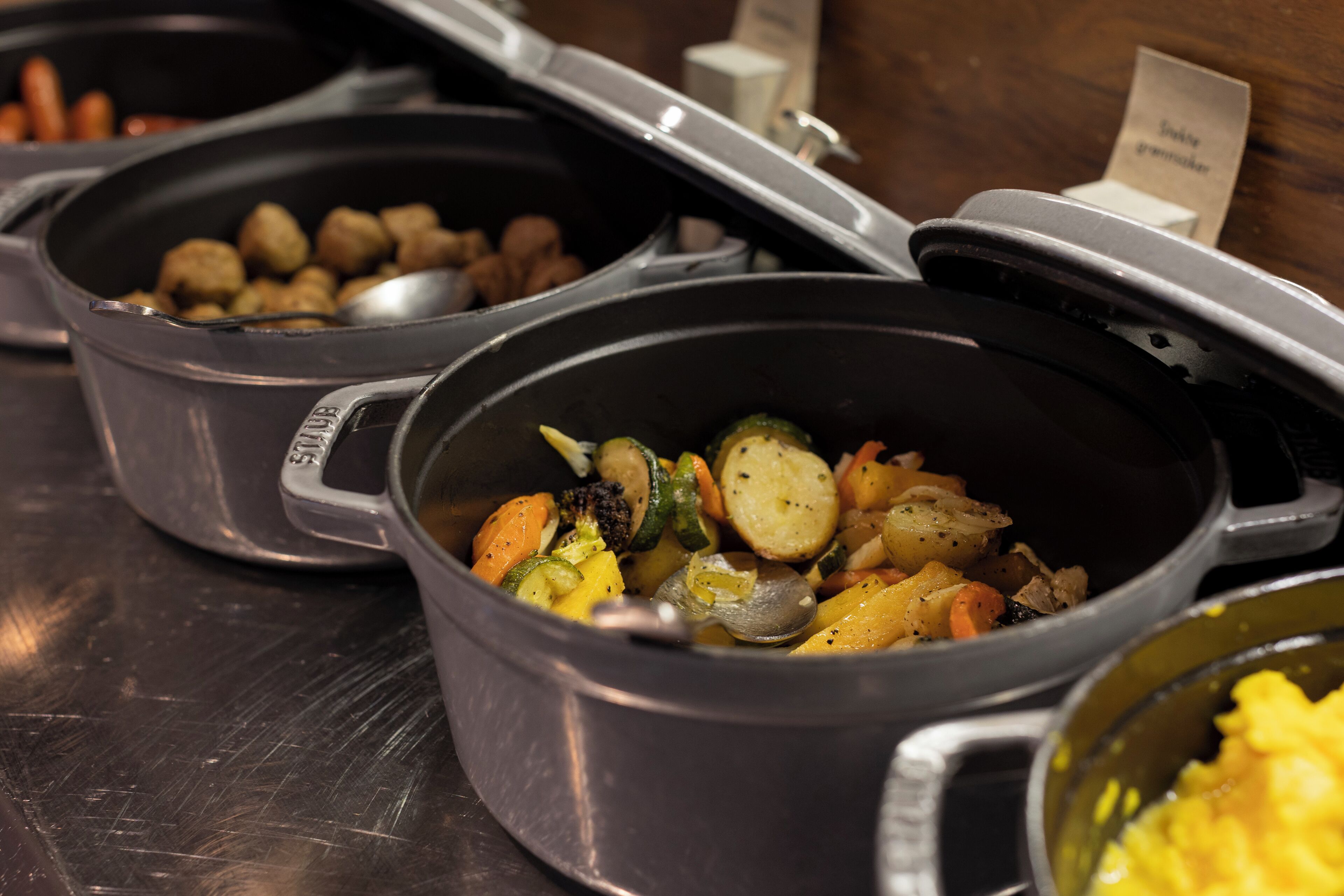 A buffet with various dishes, including vegetables and meat.