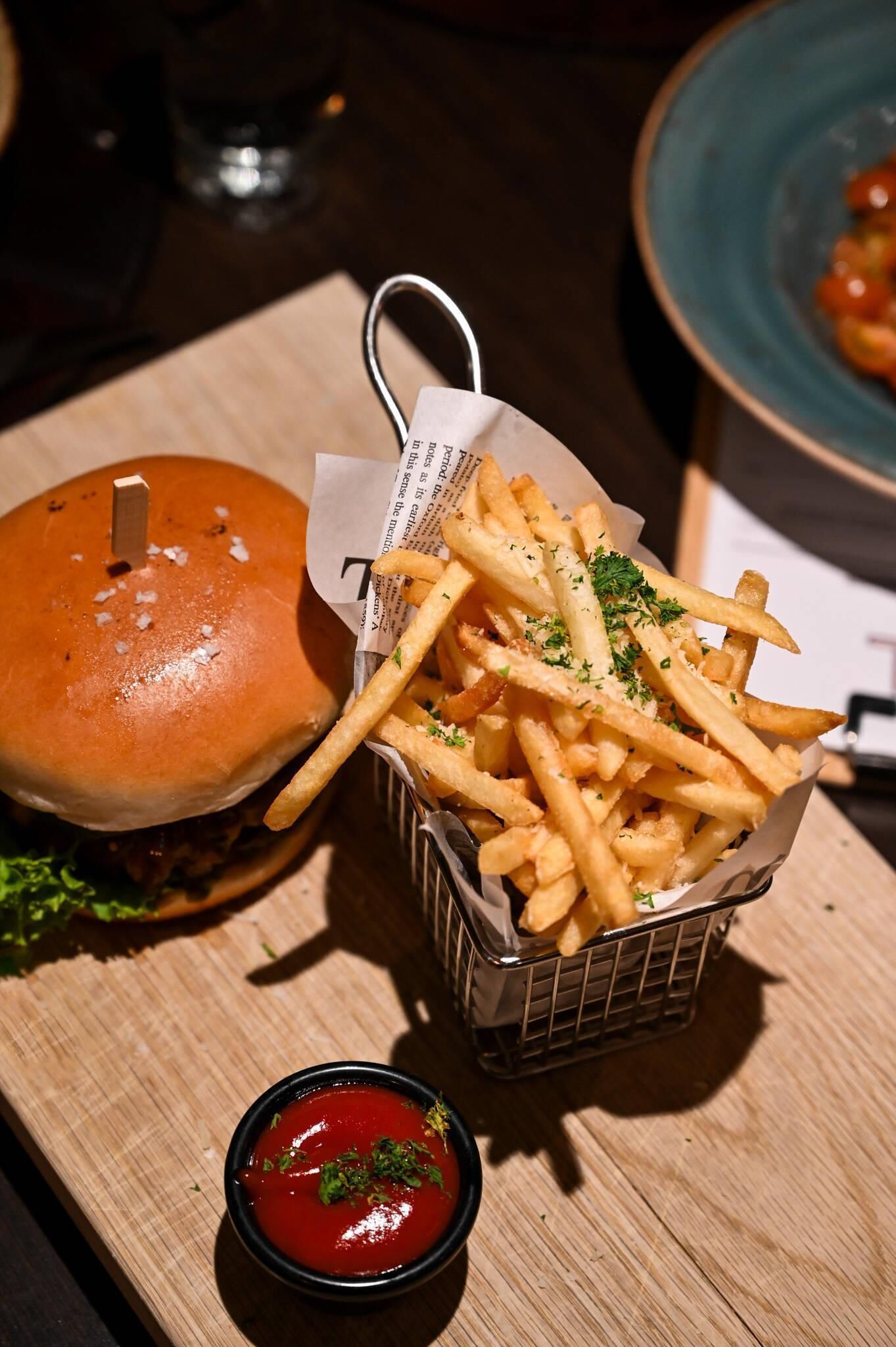 Una hamburguesa con papas fritas y kétchup sobre una mesa de madera.