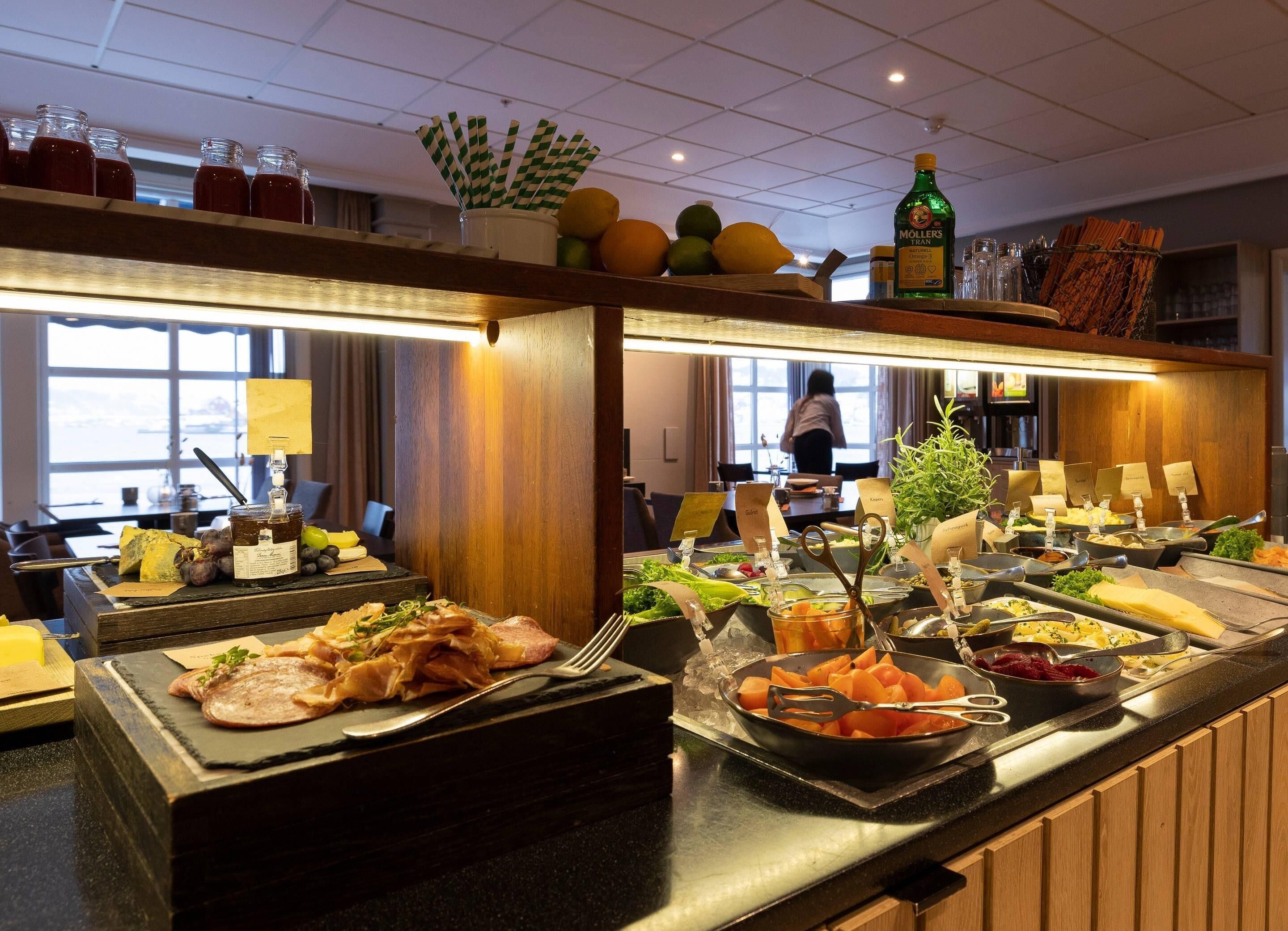 A buffet with various food items, a juice dispenser, and a bottle of oil.