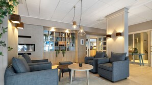 Uma área de estar moderna com sofás cinzas, uma mesa de centro redonda e iluminação pendente.
