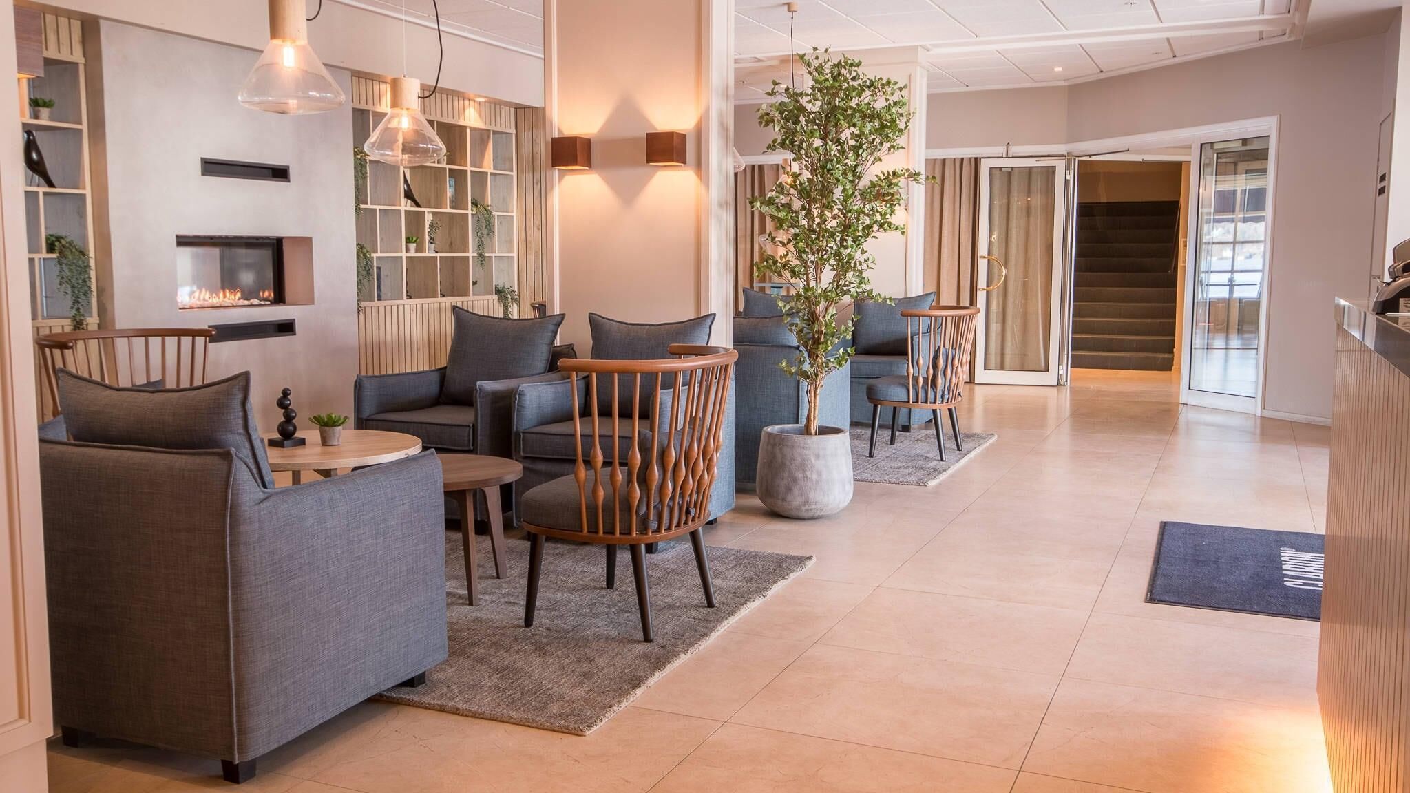 Een moderne hotellobby met banken, een salontafel, een potplant en een trap naar een andere verdieping.