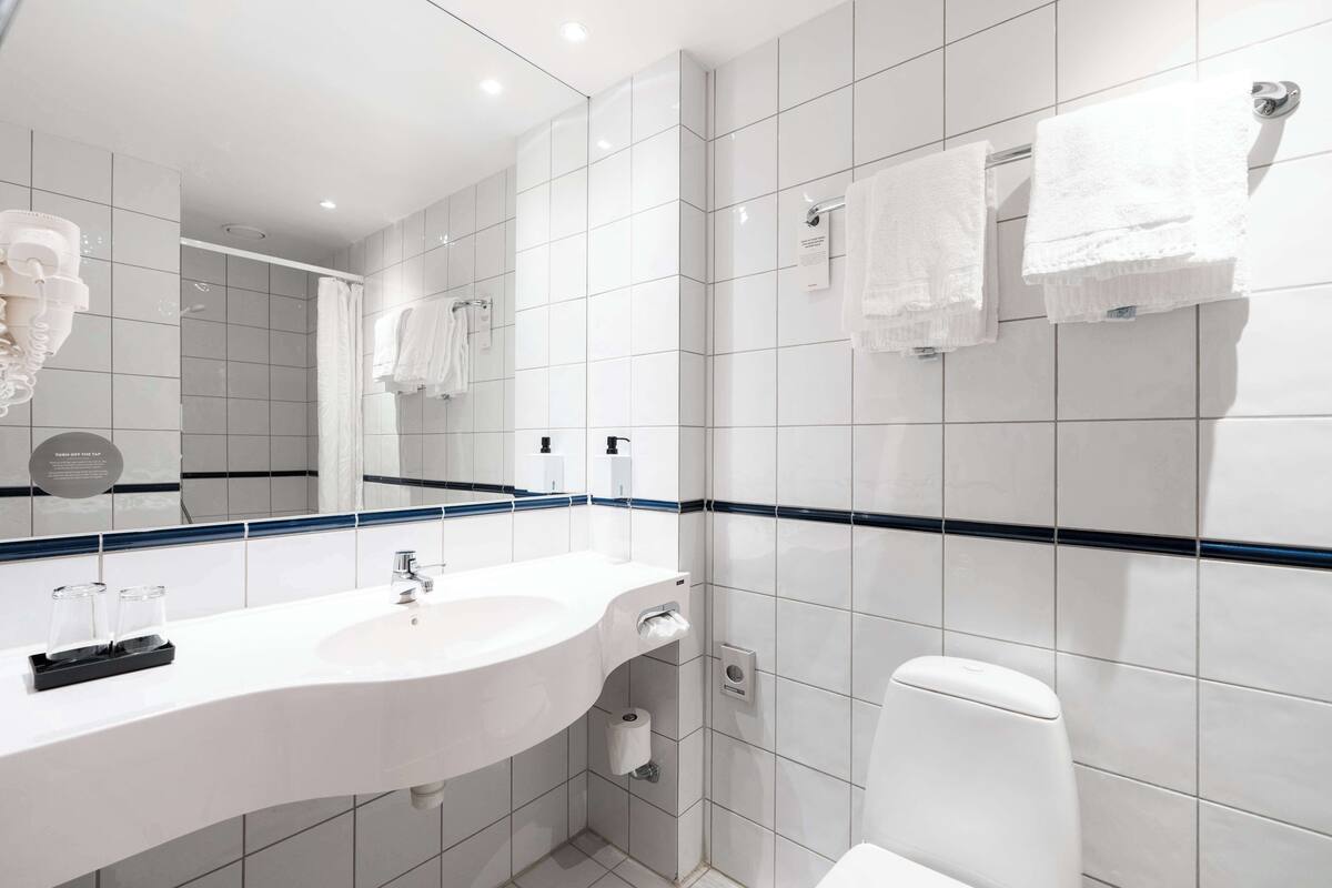 A modern bathroom with a white sink, mirror, and white toilet.