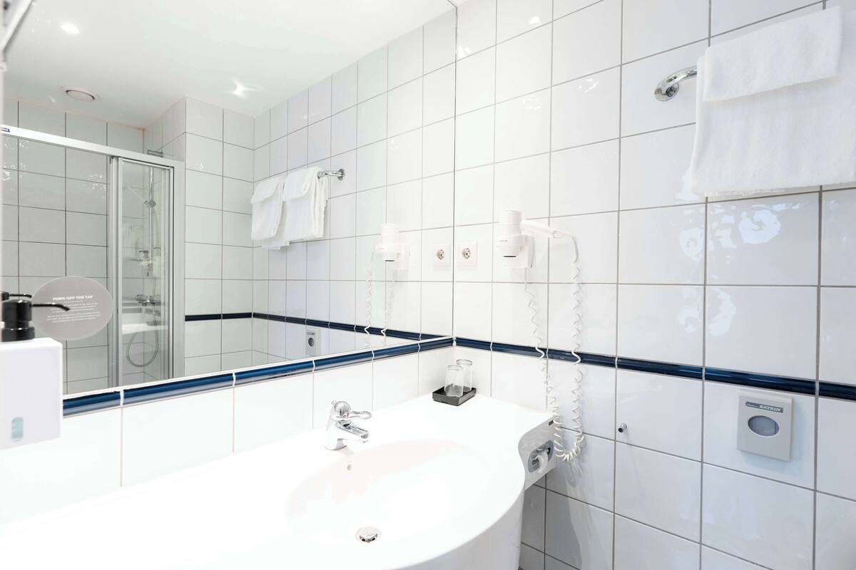 A modern bathroom with a glass-enclosed shower, a white sink, and a towel rack.