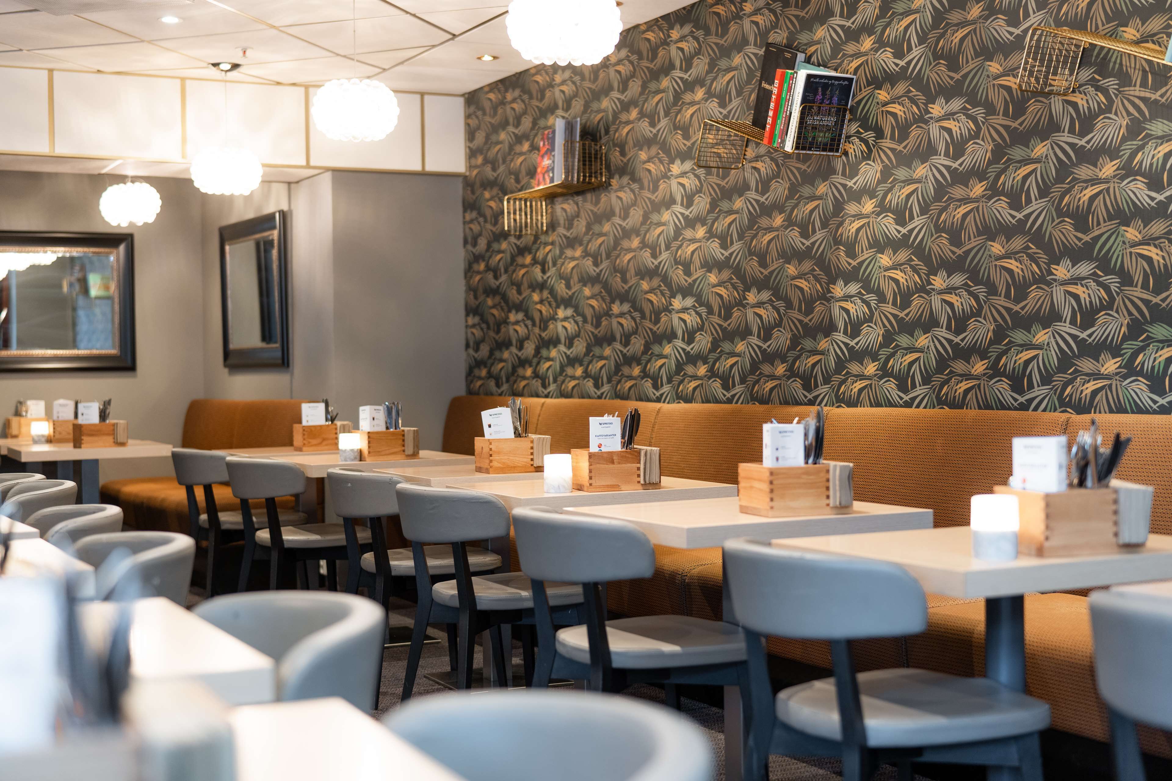 A restaurant interior with tables, chairs, a wooden bench, and a patterned wall.