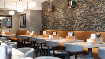 A restaurant interior with tables, chairs, a wooden bench, and a patterned wall.