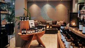 Un interior moderno con una mesa de madera mostrando varias botellas, un sofá y una pared decorativa con diseño de luna creciente.