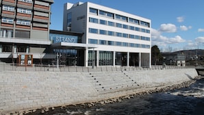 Un edificio moderno con un llamativo letrero 'STRAND', que presenta una estructura de varios pisos con amplias ventanas y un techo plano.