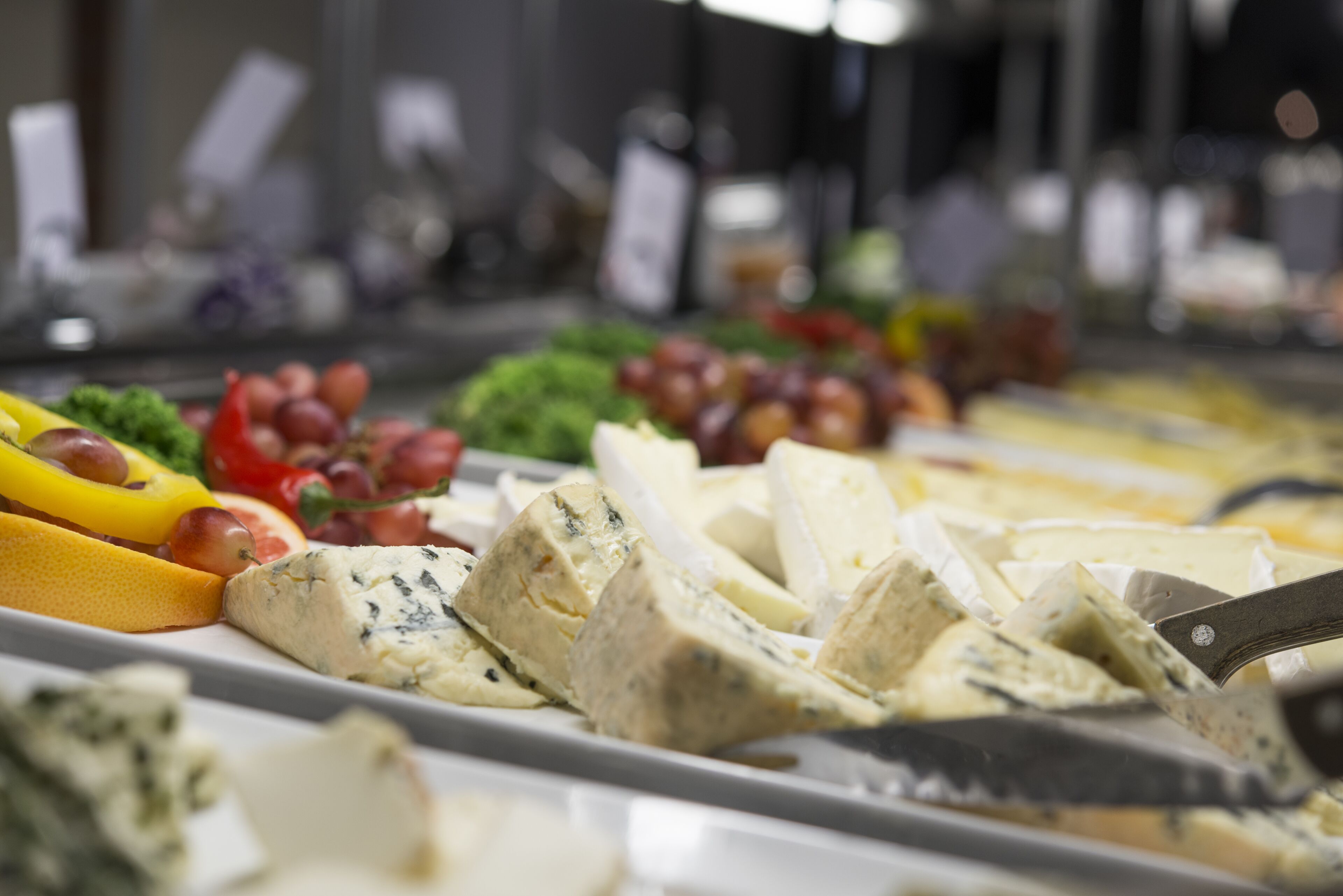 A cheese and fruit platter with various cheeses and grapes.