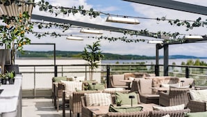 Un patio al aire libre con mobiliario de mimbre, plantas en macetas y luces colgantes.