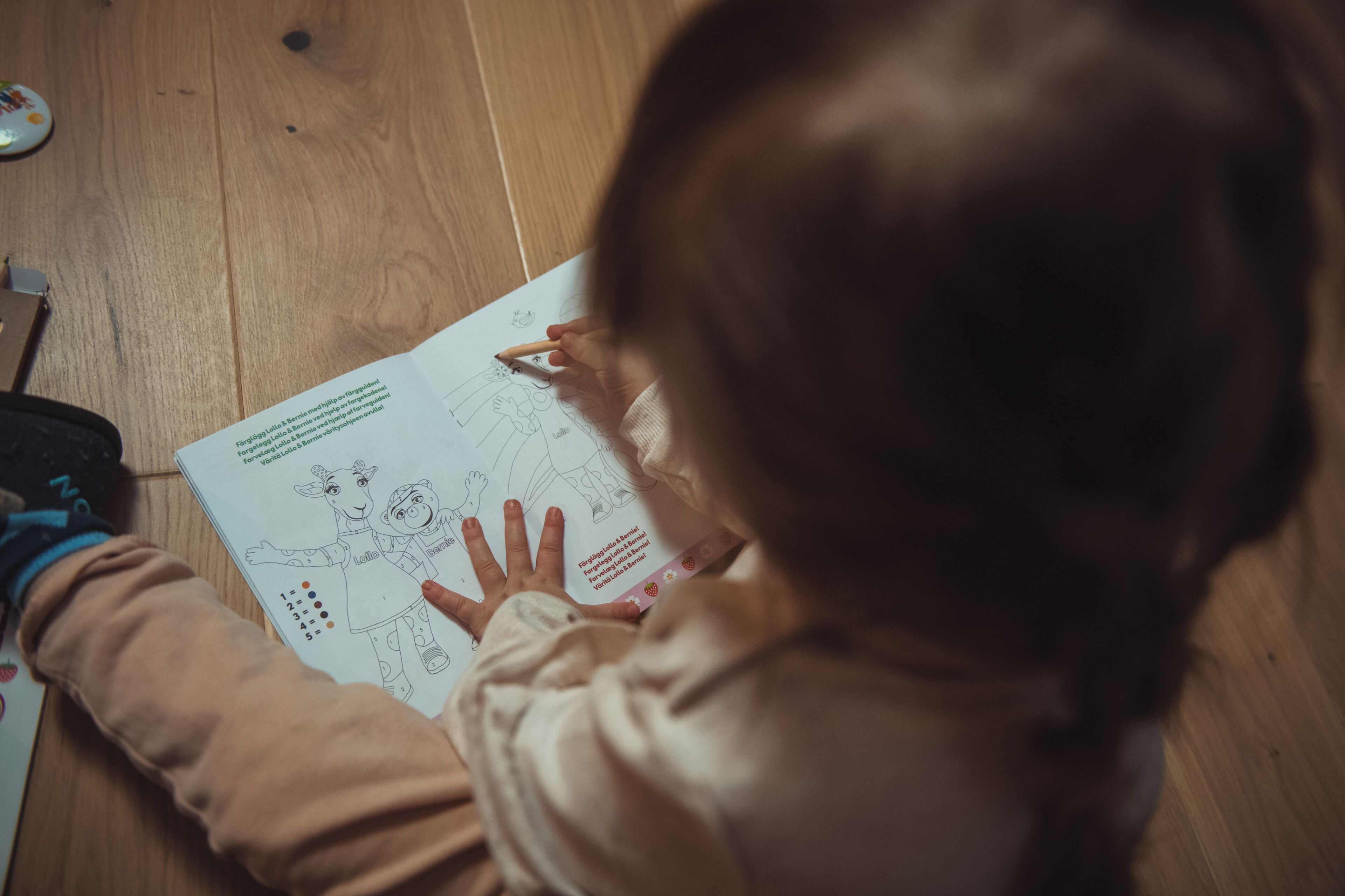 Un niño sentado en el suelo dibujando en un libro para colorear.