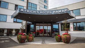 Hotel Frich Hamar con una entrada moderna, grandes macetas y una vista despejada del estacionamiento.