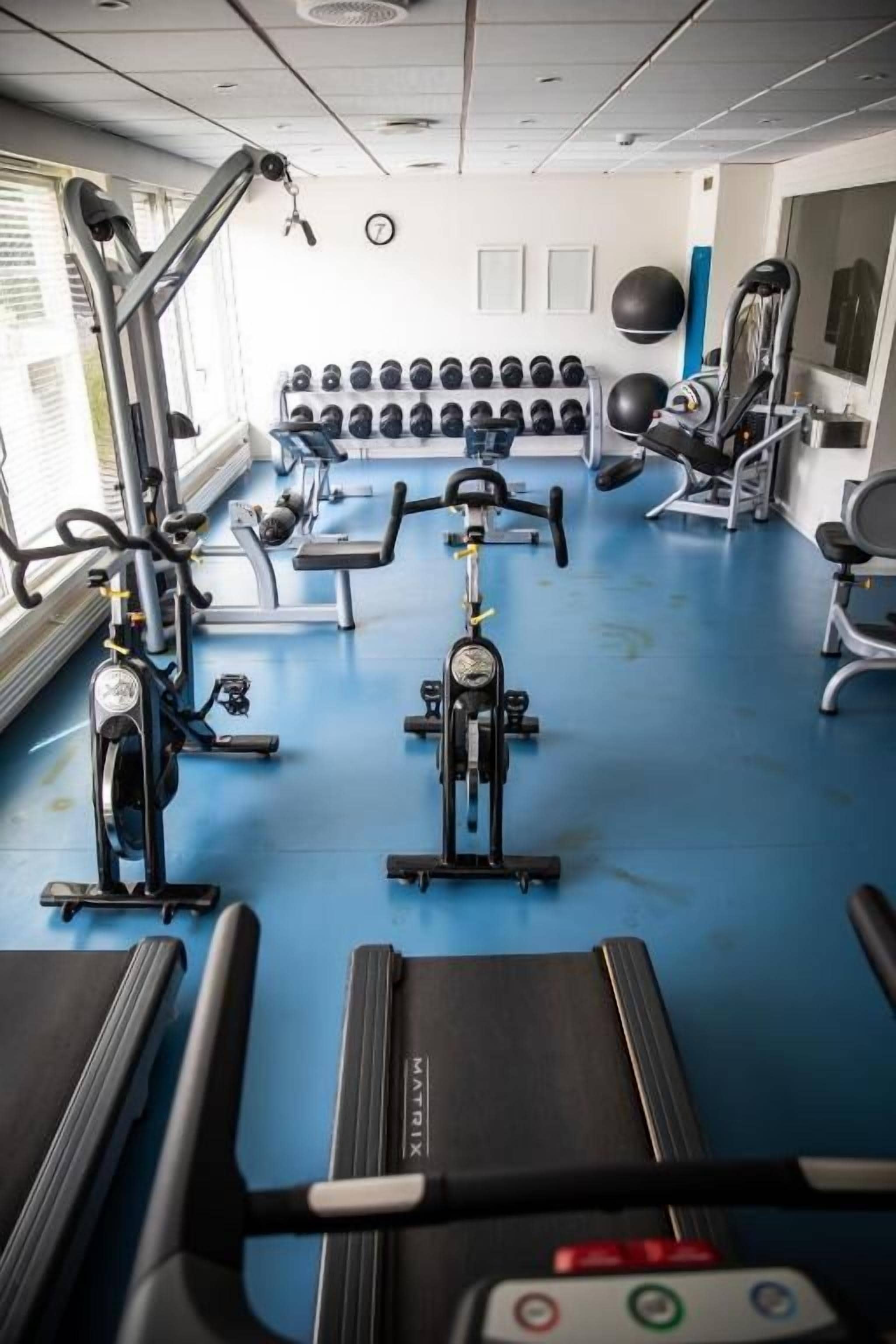 Une salle de sport équipée de divers appareils d’exercice, notamment des tapis de course, des vélos d’appartement et des appareils de musculation.