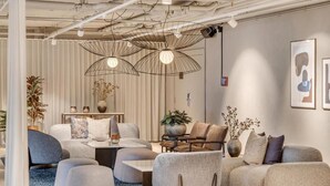 Una sala moderna con un conjunto de sofá, otomanas y una mesa de centro. Hay lámparas colgantes y una planta en maceta.