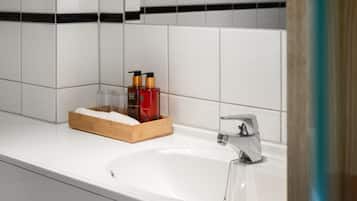 Une salle de bain avec un lavabo blanc, un porte-savon en bois et deux bouteilles de savon.
