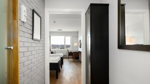 Un pasillo con pared de ladrillo, un armario negro y una cama con vista a la ciudad.