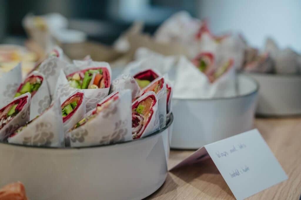 Una mesa de buffet con alimentos presentados ordenadamente en recipientes.