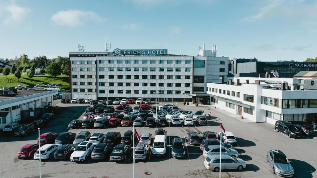 Un hotel con un estacionamiento lleno de coches y un edificio con la leyenda "FRICH'S HOTEL".