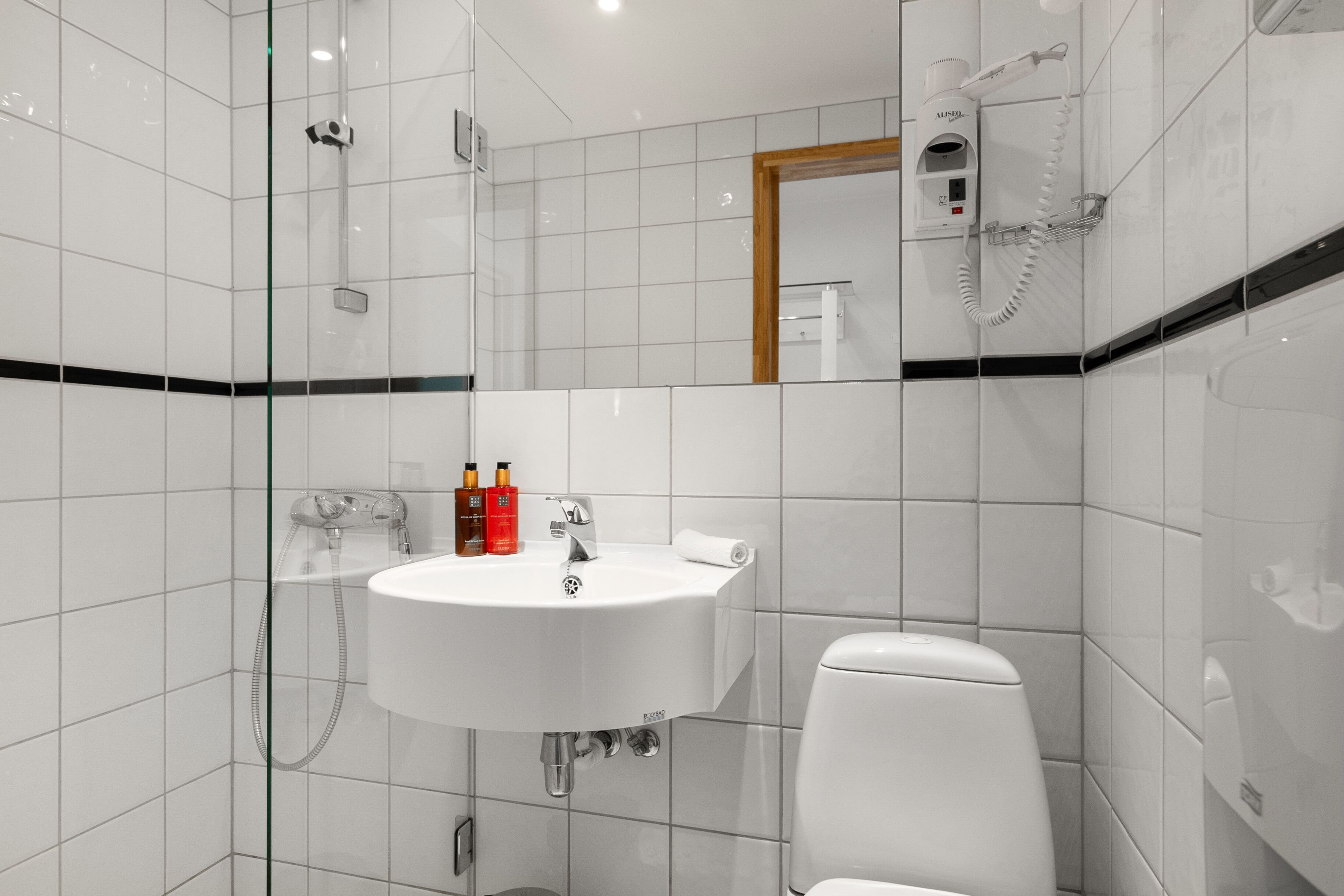 A modern bathroom with a white sink, toilet, and glass shower enclosure.