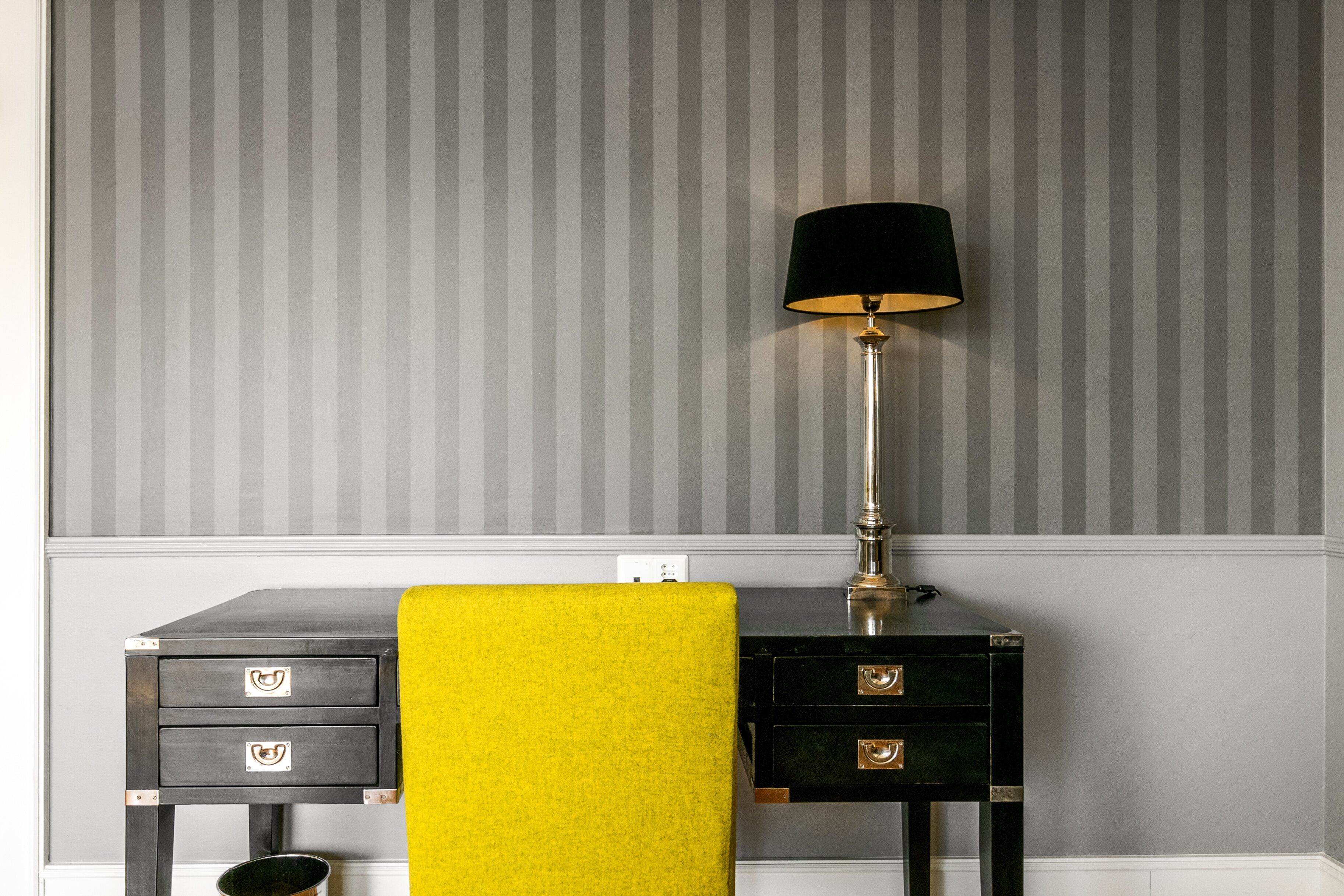 A room with a desk, a lamp, and a yellow towel.