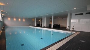 Una piscina interior con suelo y pared de azulejos, e iluminación empotrada en el techo.