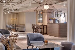 A modern interior with a seating area, a bar, and a reception desk. -  Frich´s Hotel Hamar (Ringsaker)