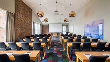A conference room with hexagonal patterned carpet, wooden tables, and black chairs.