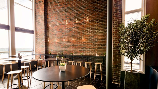 A modern interior with brick walls, round tables, and potted plants. - Scandic Hammerfest (Hammerfest)
