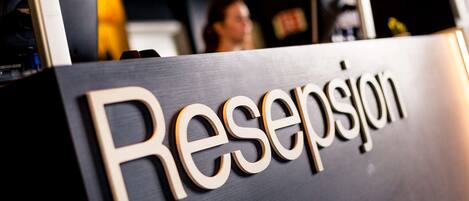 Un comptoir d’accueil sur lequel est inscrit le mot « Resepjon ».