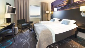 A hotel room with a bed, desk, chair, and a large window. - Scandic Hammerfest (Hammerfest)