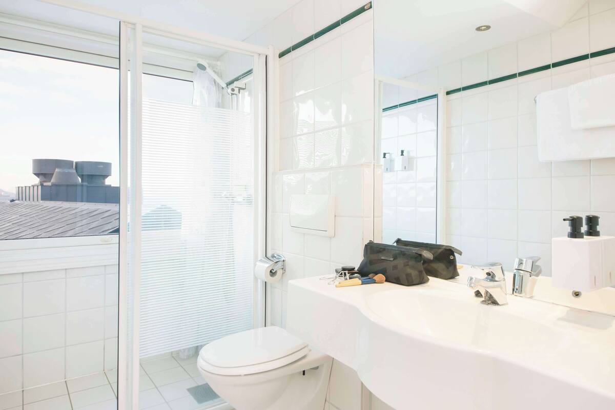 Ein modernes Badezimmer mit Toilette, Waschbecken und großem Spiegel.