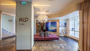 A modern hotel lobby with a staircase, a seating area with a chandelier, and a large window. - Scandic Harstad (Harstad)