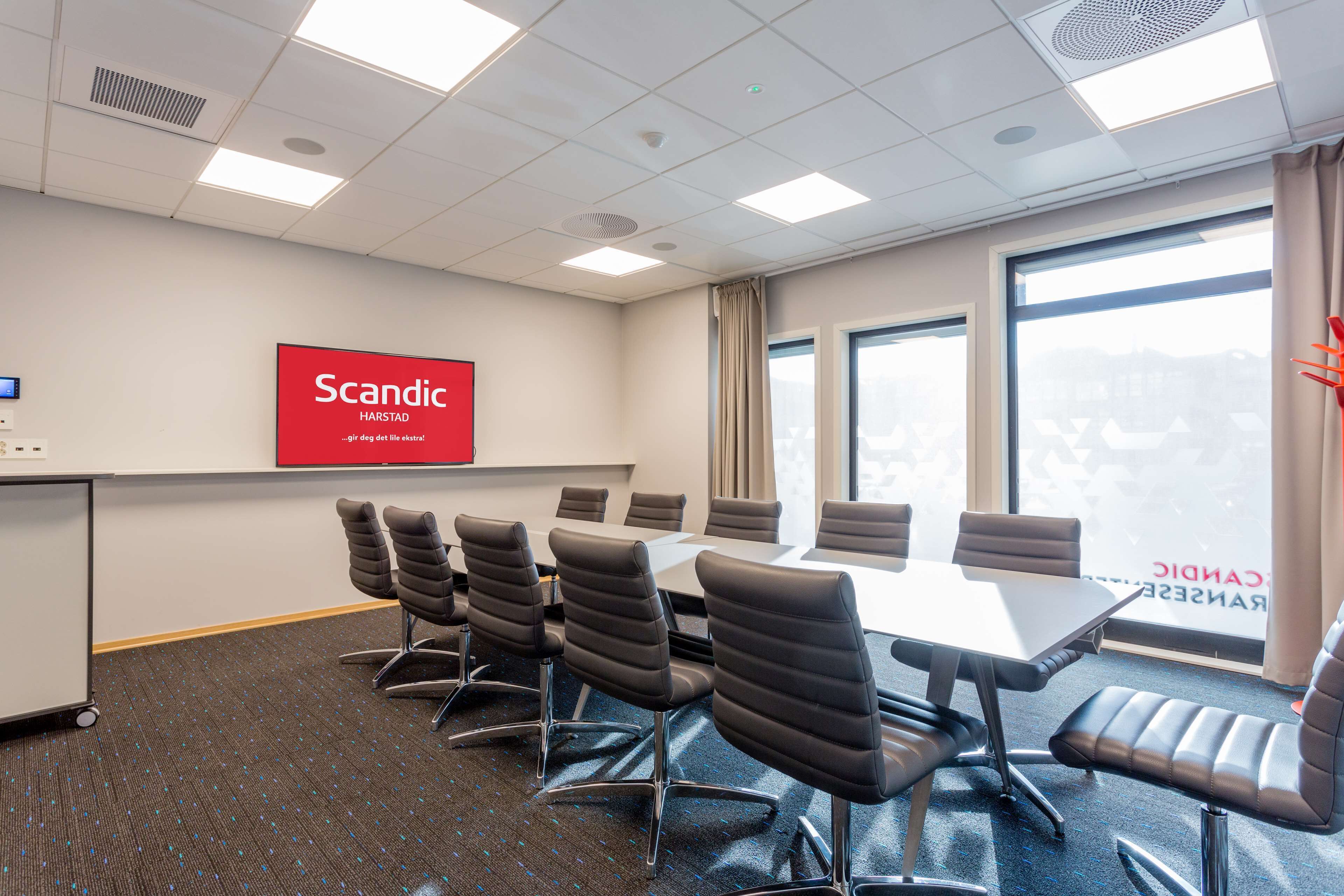 A conference room with a large table, six chairs, and a red sign on the wall.