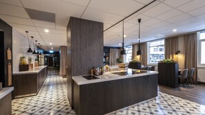 A modern kitchen with a central island, dark wood cabinetry, and a patterned tile floor. - Scandic Harstad (Harstad)