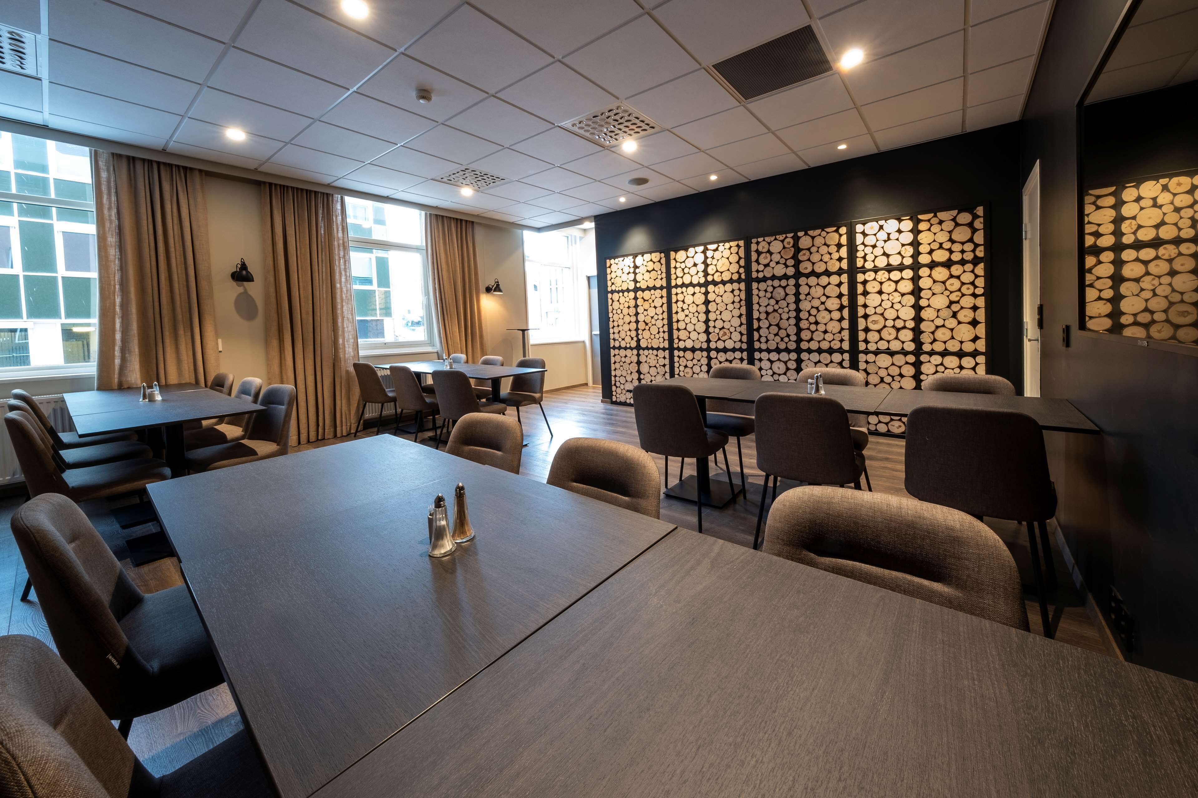 A conference room with a long table, multiple chairs, and a decorative wall panel.