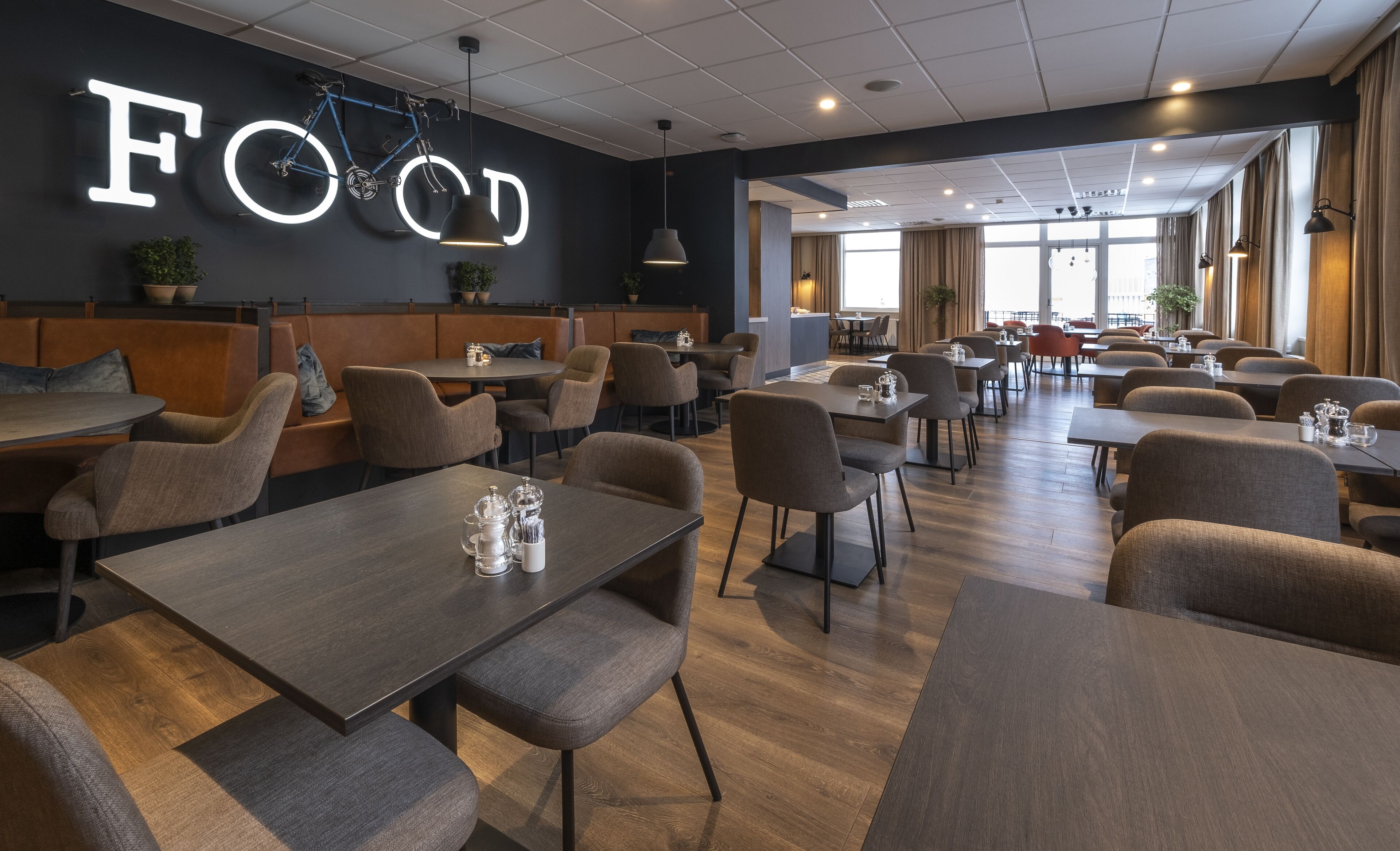 A spacious restaurant with a modern interior, featuring a prominent 'FOOD' sign, comfortable seating, and a clean, well-lit environment.