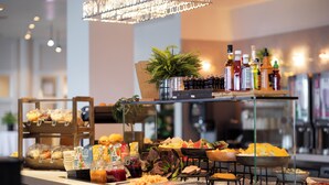 Disposición de bufé con diferentes alimentos, salsas y una planta decorativa.