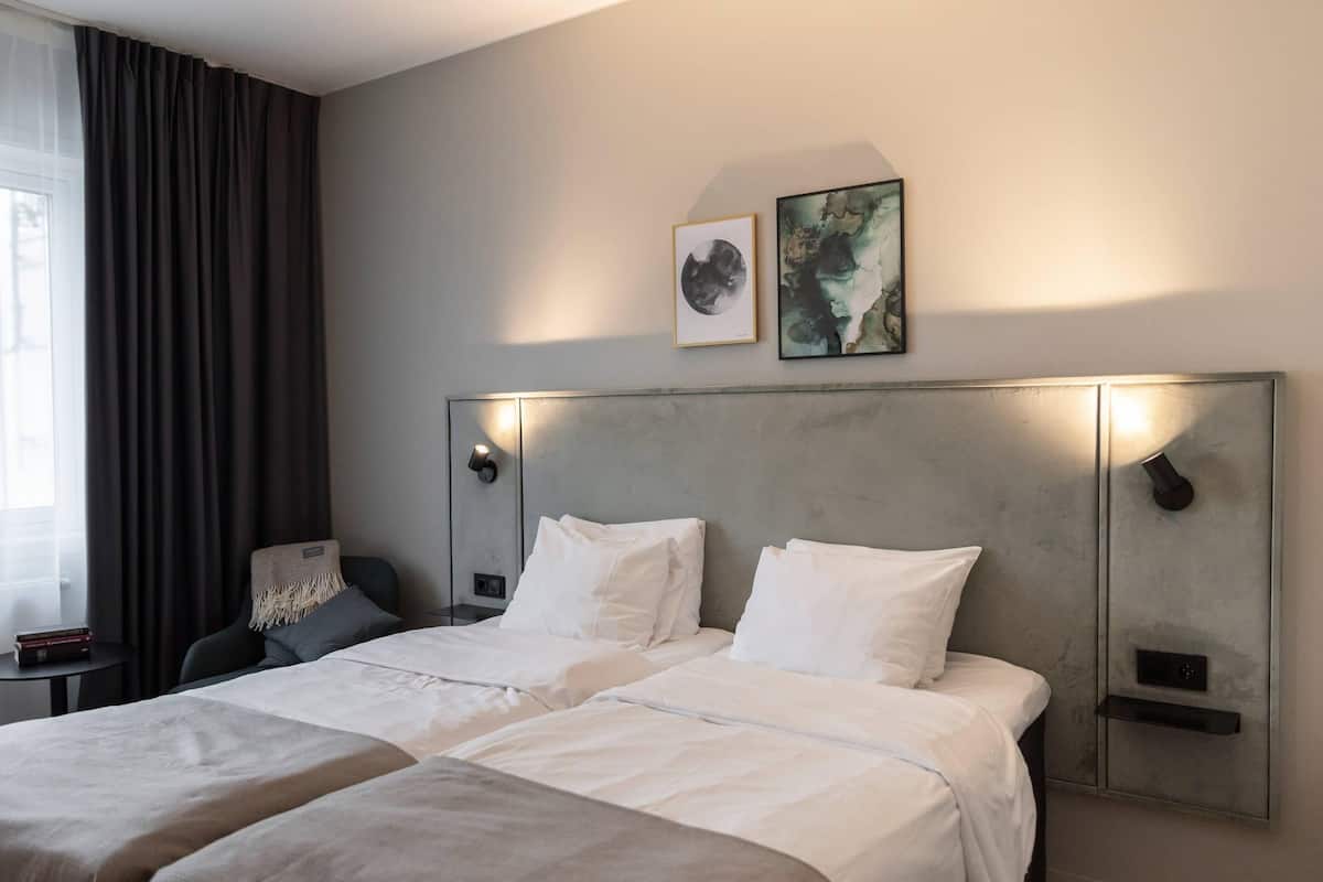 Una habitación de hotel con una cama grande, dos mesitas de noche, una silla y una obra de arte en la pared.