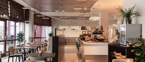 A modern restaurant with a central island, dining tables, and chairs.