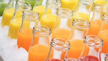 A variety of colorful beverages in glass bottles on ice.