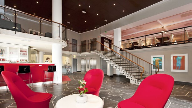 A spacious lobby with a central seating area, a staircase, and a reception desk. - Thon Hotel Saga (Haugesund)