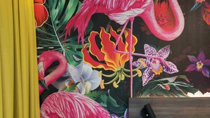 A room with a vibrant floral mural, a yellow armchair, a small round table, and a wooden bedside table with a lamp. - Thon Hotel Saga (Haugesund)