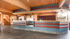 A reception area with a wooden ceiling, a reception desk with a glass display case, and a view of the outdoors. - Scandic Nordkapp (Nordkapp)