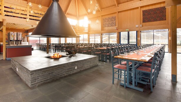 A spacious indoor dining area with a stone bar and multiple tables and chairs. - Scandic Nordkapp (Nordkapp)