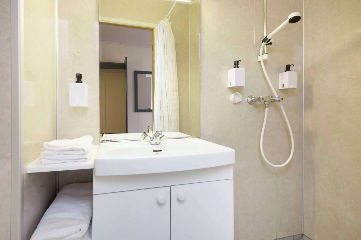 A modern bathroom with a white sink, mirror, and shower.