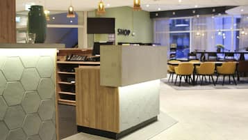 A modern reception area with a wooden counter, hexagonal patterned wall, and yellow chairs.