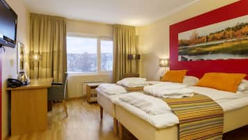 Habitación de hotel con cama, escritorio, silla, televisor y un cuadro en la pared.