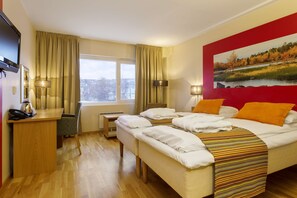 Habitación de hotel con cama, escritorio, silla, televisor y un cuadro en la pared.