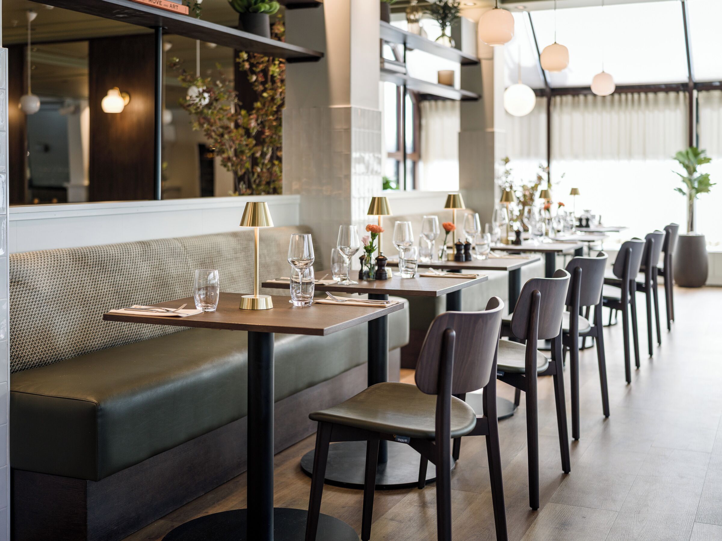 En restaurant med en lang disk, siddepladser i båse og moderne indretning.