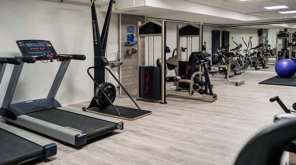 Un gimnasio con cintas de correr, elípticas y pesas sueltas.